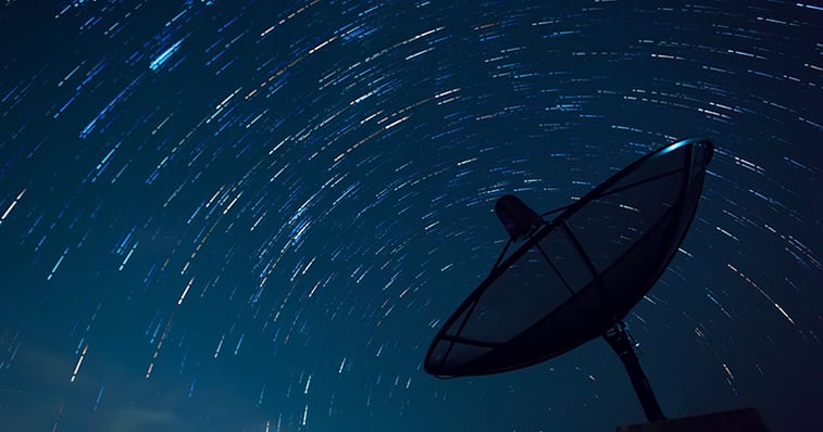 Antenna pointing towards a sky full of satellites at night 